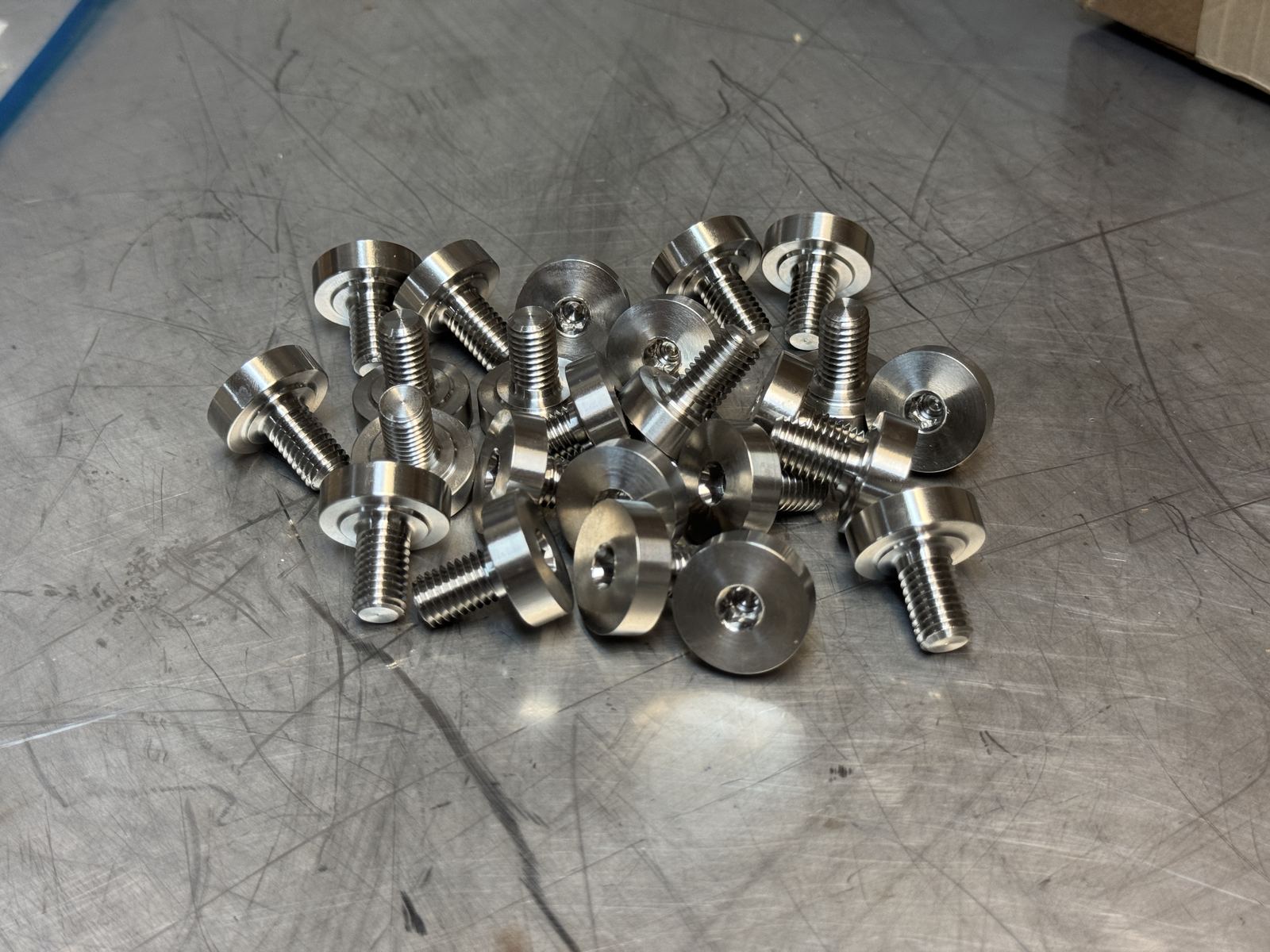 Pile of stainless steel shoulder bolts on machined finish surface